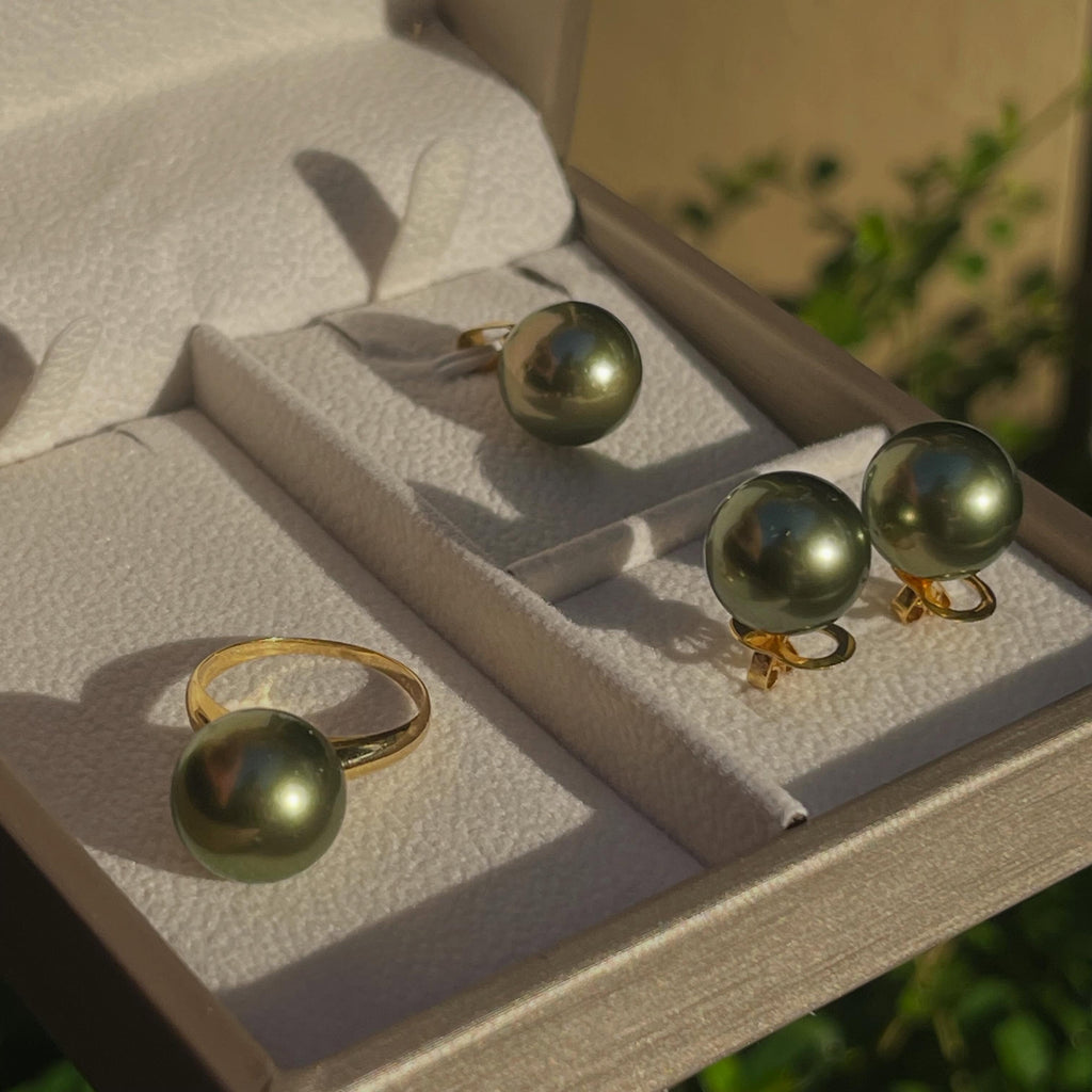13mm pistachio green South Sea pearl ring and earrings set in 14K gold displayed in a jewelry box under natural light.