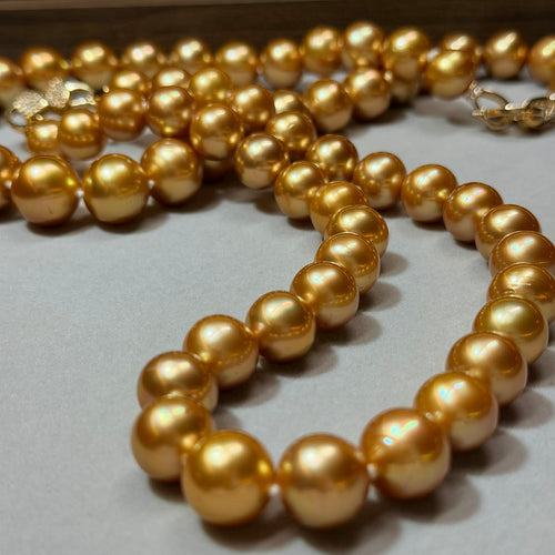 Gold pearl necklace on a light gray surface