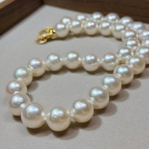 Pearl necklace with a gold clasp on a light gray surface